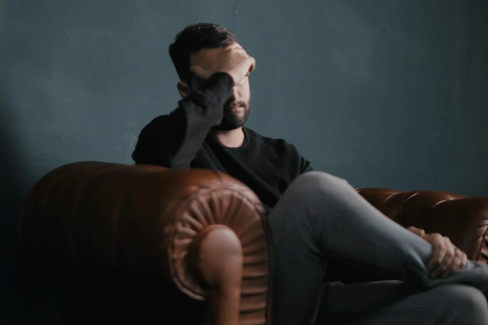 A man sitting on a couch, head in hand